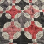 Custom quilting on a red and black nine patch variation
